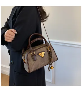 Detail of vintage brown leather bowling bag with bell charm and gold triangle logo