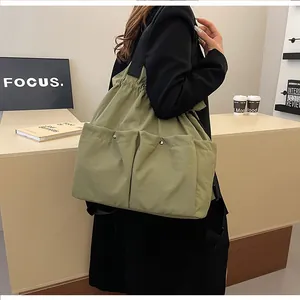 Detailed view of olive green oversized tote bag featuring dual snap pockets and drawstring closure
