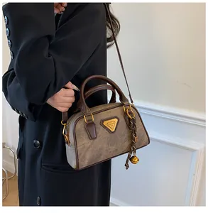 Detail of vintage brown Boston bag with metal logo, bell pendant and textured finish