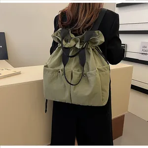 Detail view of sage green drawstring backpack with dual pockets and nylon texture