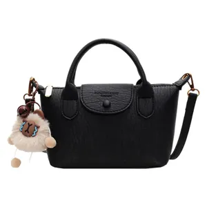 Minimalist black lychee texture dumpling bag with top handle and crossbody strap