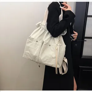Detail view of large capacity cream tote bag with metallic buckle pockets and drawstring
