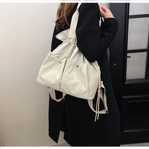 Detailed back view of model wearing a minimalist beige drawstring backpack with rivets