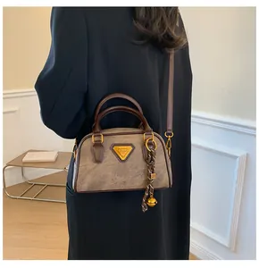 Detail of vintage brown Boston bag featuring golden triangle logo and tassel charm