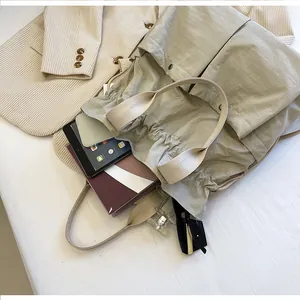 Detail view of spacious beige nylon tote bag with books, tablet, and travel essentials