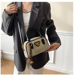 Detail view of grey suede bowling bag with black leather straps and gold metal triangle logo