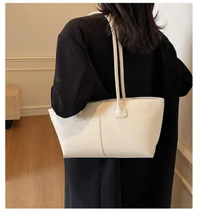 Detail of a white minimalist faux leather tote bag showing fine texture and stitching