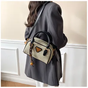 Detail of vintage canvas crossbody bag with leather trim and triangle metal logo
