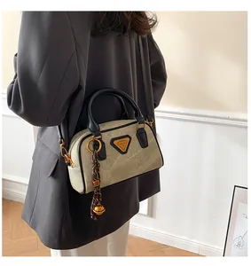 Detail of Boston bowling bag in beige suede with leather handles and gold bell charm