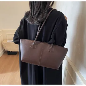 Detailed view of deep brown large leather tote bag worn as a shoulder underarm bag