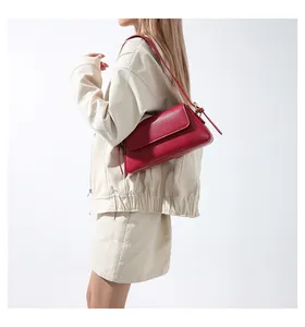 Close-up of deep red leather baguette bag with minimalist flap and gold metal buckle