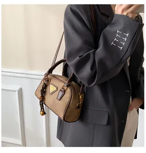 Detail of vintage brown shoulder bag with metal logo and contrast leather handles