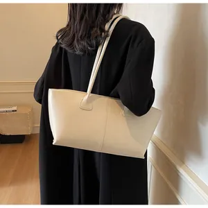 Side view of a creamy white leather tote bag with slim shoulder straps and vertical stitching