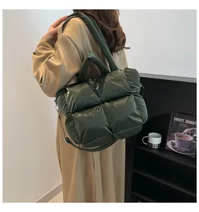 Detail of dark green quilted puffer tote bag with glossy finish and wide shoulder strap