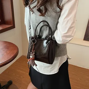 Bolso tote vintage de charol marrón oscuro con colgante de oso y correa ajustable de hombro