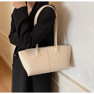 Close-up of cream leather tote bag with vertical stitching on black long coat