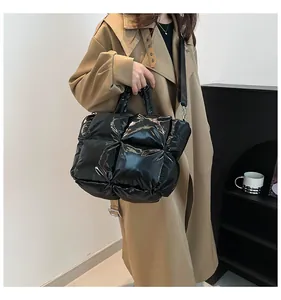 Detail of black padded quilted tote bag shown in a stylish handheld carrying scene