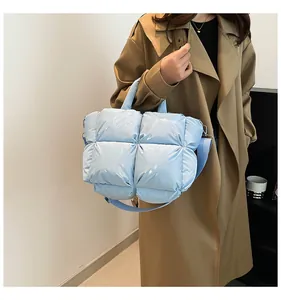 Macro shot of light blue quilted crossbody bag with high-gloss finish and wide strap