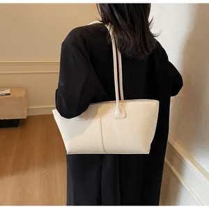 Detailed back view of a beige leather tote bag worn over a black winter coat