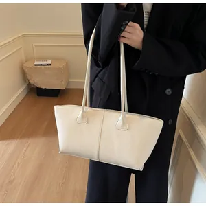 Detail of minimalist cream leather tote bag with long shoulder straps and fine grain texture