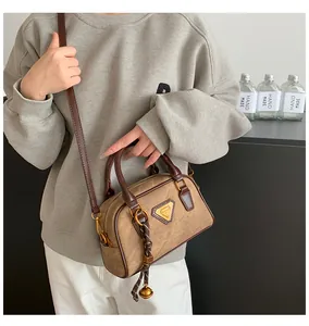 Detail shot of vintage brown Boston bag with golden logo plaque and woven bell charm