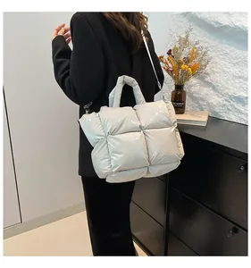 Silver quilted puffer bag worn crossbody showing the metallic finish and padded texture
