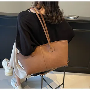 Detail of a large brown faux leather tote bag with long handles for shoulder carry