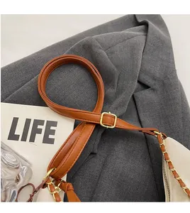 Detail of adjustable leather and gold chain shoulder strap on a beige tote bag