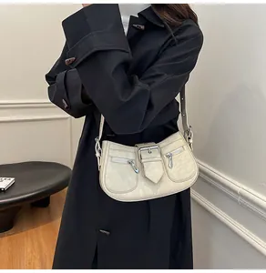 Detailaufnahme der cremeweißen Kunstledertasche mit Metallschnalle und zwei Reißverschlusstaschen