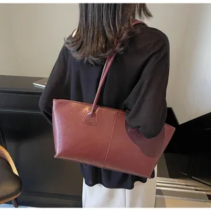 Detail view of the matte dark red leather tote bag showing fine grain and stitching