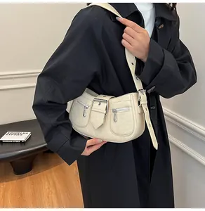 Detail der cremeweißen Leder-Schultertasche mit Metallschnalle und Reißverschlüssen