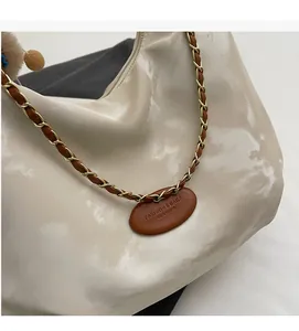 Detail of cream tote bag with chain strap, plush pendant and fashion leather tag