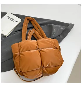 Detail of a brown quilted puffer handbag with padded handles and an adjustable shoulder strap