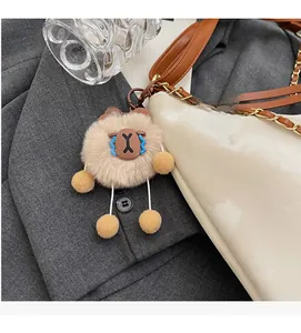 Detail of a plush bear charm with blue teardrop accents attached to a white chain handbag