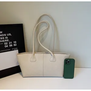 Close-up of minimalist cream tote bag with long handles and sleek leather texture