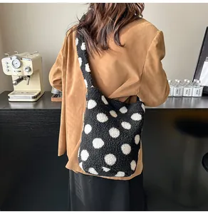 Detalle de bolso tote de felpa suave a lunares blancos y negros con correa ancha
