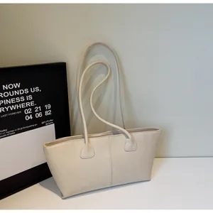 Detail shot of cream white leather tote bag with vertical stitching and slim straps