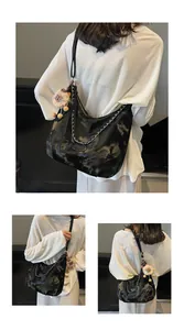 Detail of glossy black hobo bag featuring silver chain and cute lion plush charm