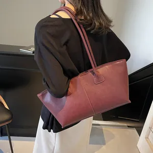 Elegant burgundy matte leather tote bag with vertical stitching shown on model shoulder