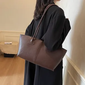 Classic dark brown large capacity tote bag with dual straps shown on shoulder