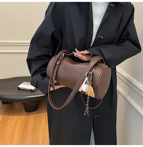 Nahaufnahme der braunen Zylindertasche mit Prägung und kreativem Baseball-Anhänger