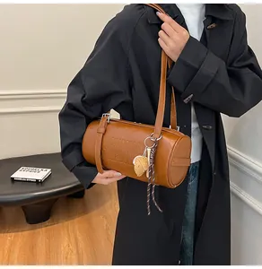 Nahaufnahme der braunen Zylindertasche aus Leder mit Prägebuchstaben und Blattanhänger