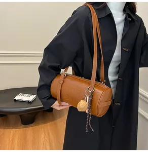 Detail einer braunen Leder-Zylindertasche mit Prägebuchstaben und Baseball-Anhänger