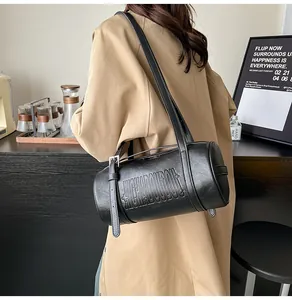 Detailaufnahme der schwarzen Zylinder-Tasche aus Leder mit Buchstabenprägung und Schnalle