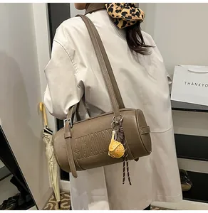 Seitenansicht der braunen Vintage-Zylindertasche mit geprägten Buchstaben und Anhänger