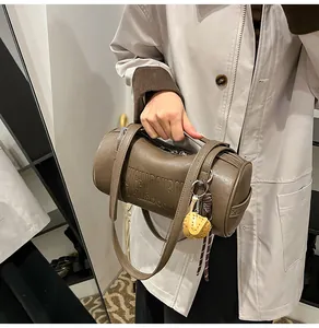 Makro-Detail der braunen Vintage-Zylindertasche aus Leder mit Prägung und gelbem Anhänger