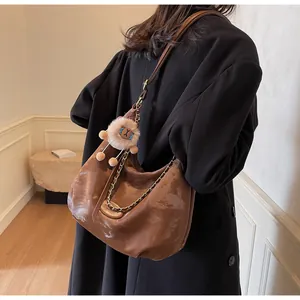 Brown leather hobo bag with lion charm shown on a model in a minimalist setting