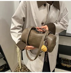 Details der braunen Zylindertasche im Vintage-Stil mit Prägung und Erdbeer-Anhänger