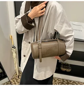 Details der braunen Zylinder-Schultertasche mit Buchstabenprägung und seitlicher Schnalle