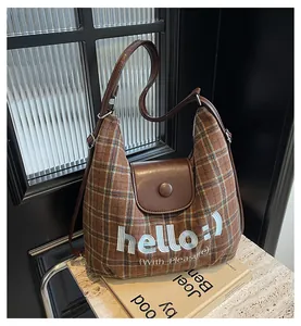 Close-up of brown plaid wool texture and leather magnetic closure on the crossbody bag